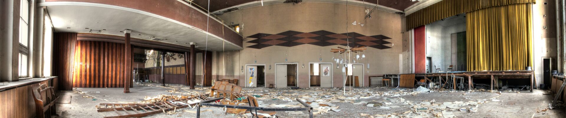Verlassener Saal mit Bühne und Balkon.