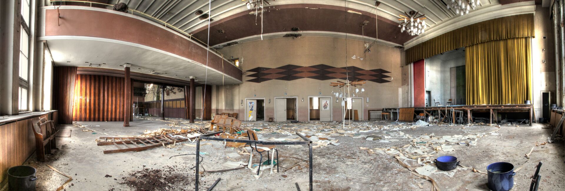 Verlassener Saal mit Bühne und Balkon.