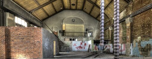 Geräumige Industriehalle mit Ketten und Graffiti.