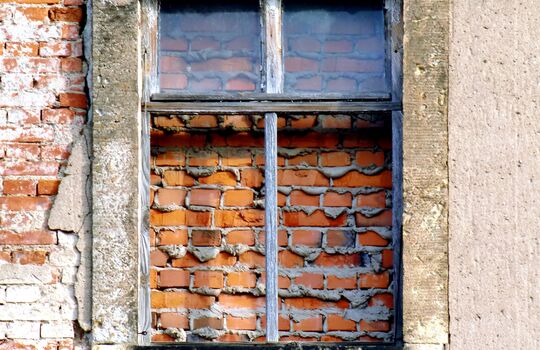 Vermauertes Fenster in alter Backsteinwand.