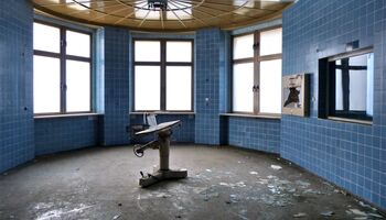 Runder, verlassener Raum mit blauen Fliesen.